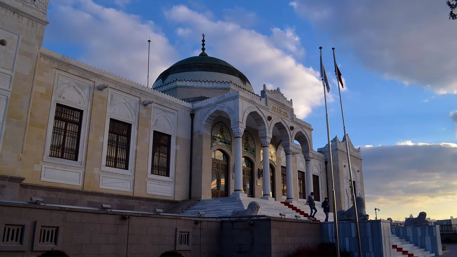 The domed entrance and stone façade of Ankara Ethnography Museum beneath a clouded sky.