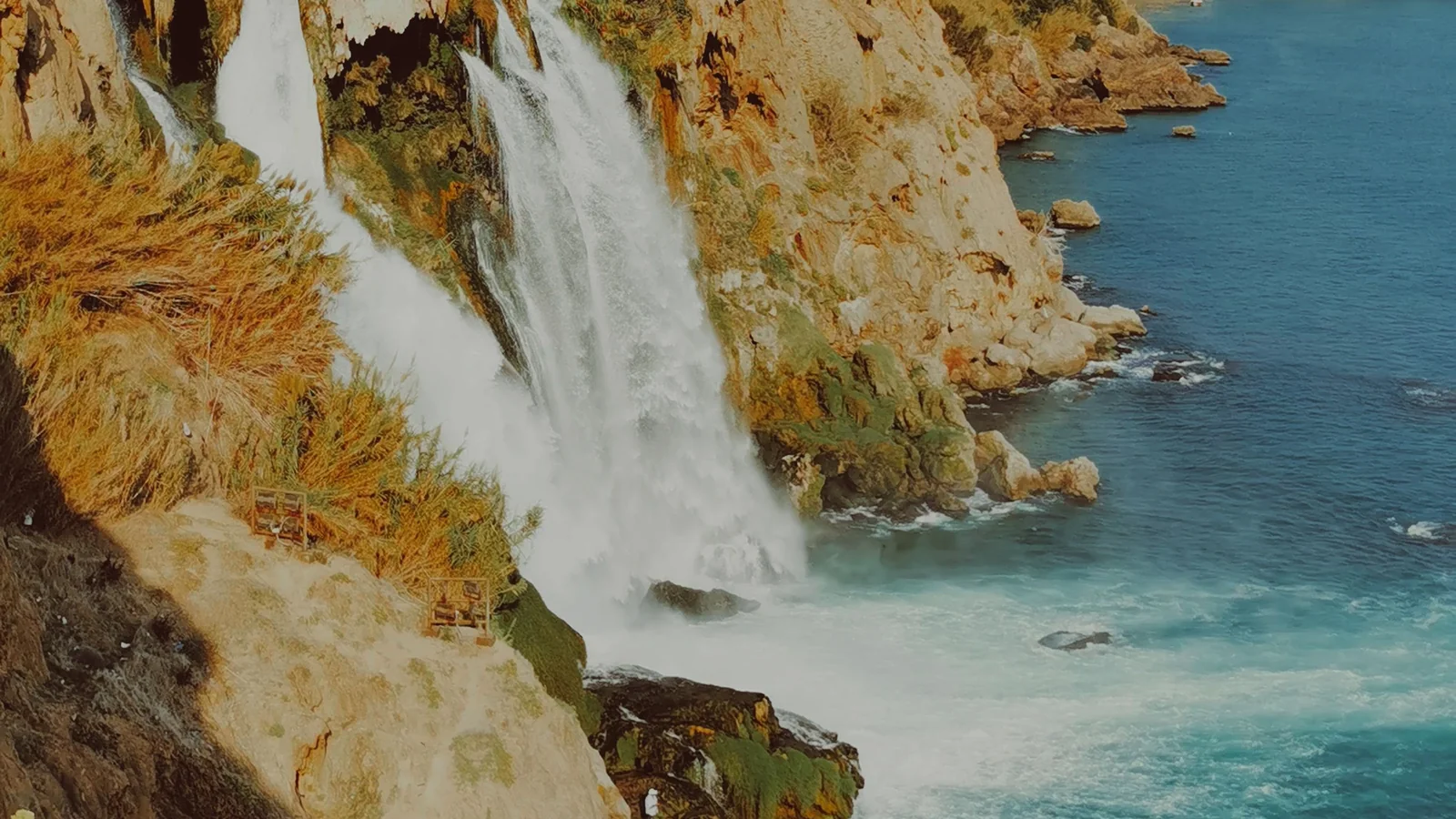 Lower Düden’s white streams falling past Antalya’s sunlit coastal rock into the blue Mediterranean.