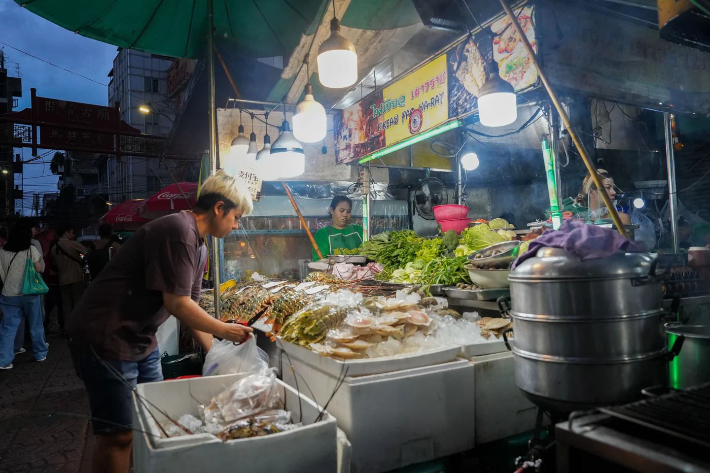 A food stall with produce and seafood at night on Yaowarat Road in Bangkok.