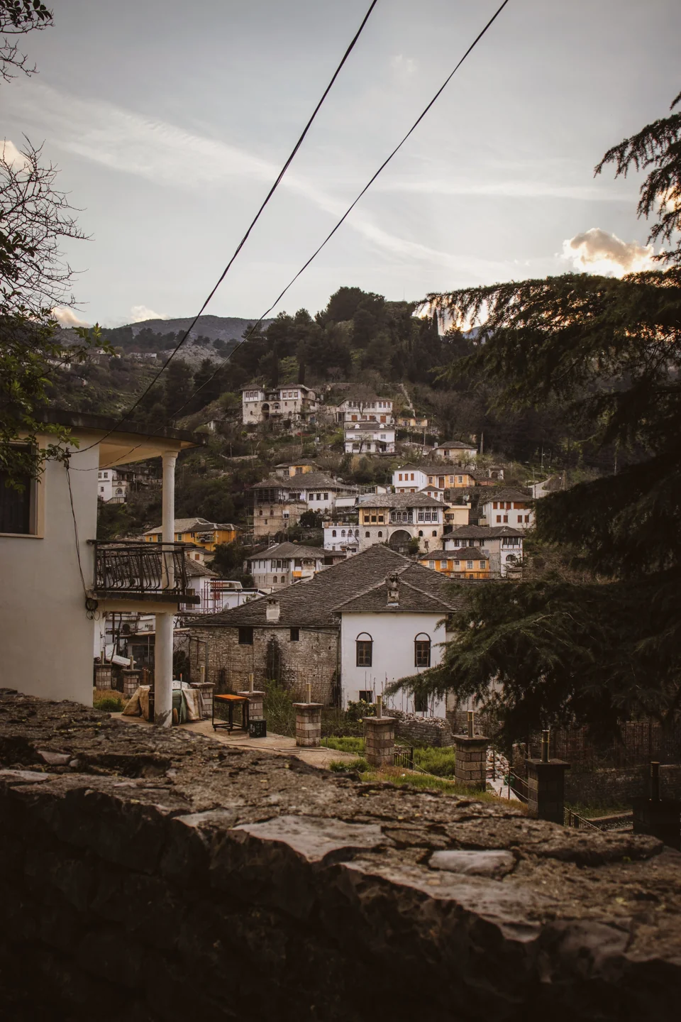 Stone-roofed historic houses rising across a hillside in Gjirokastër