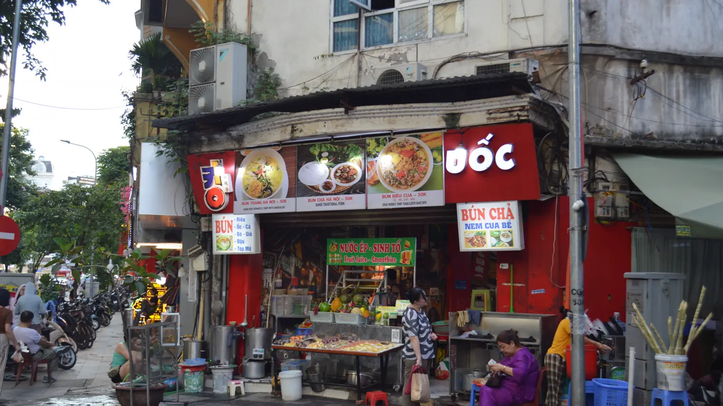 A Hanoi vendor prepares a bowl of bún chả at a street-side food stall.