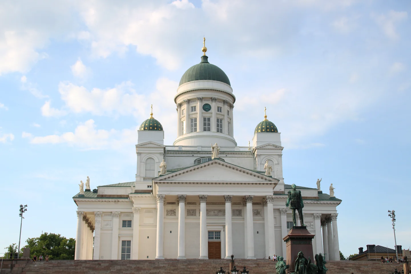 Helsinki Cathedral’s white façade and green domes beneath a partly cloudy sky