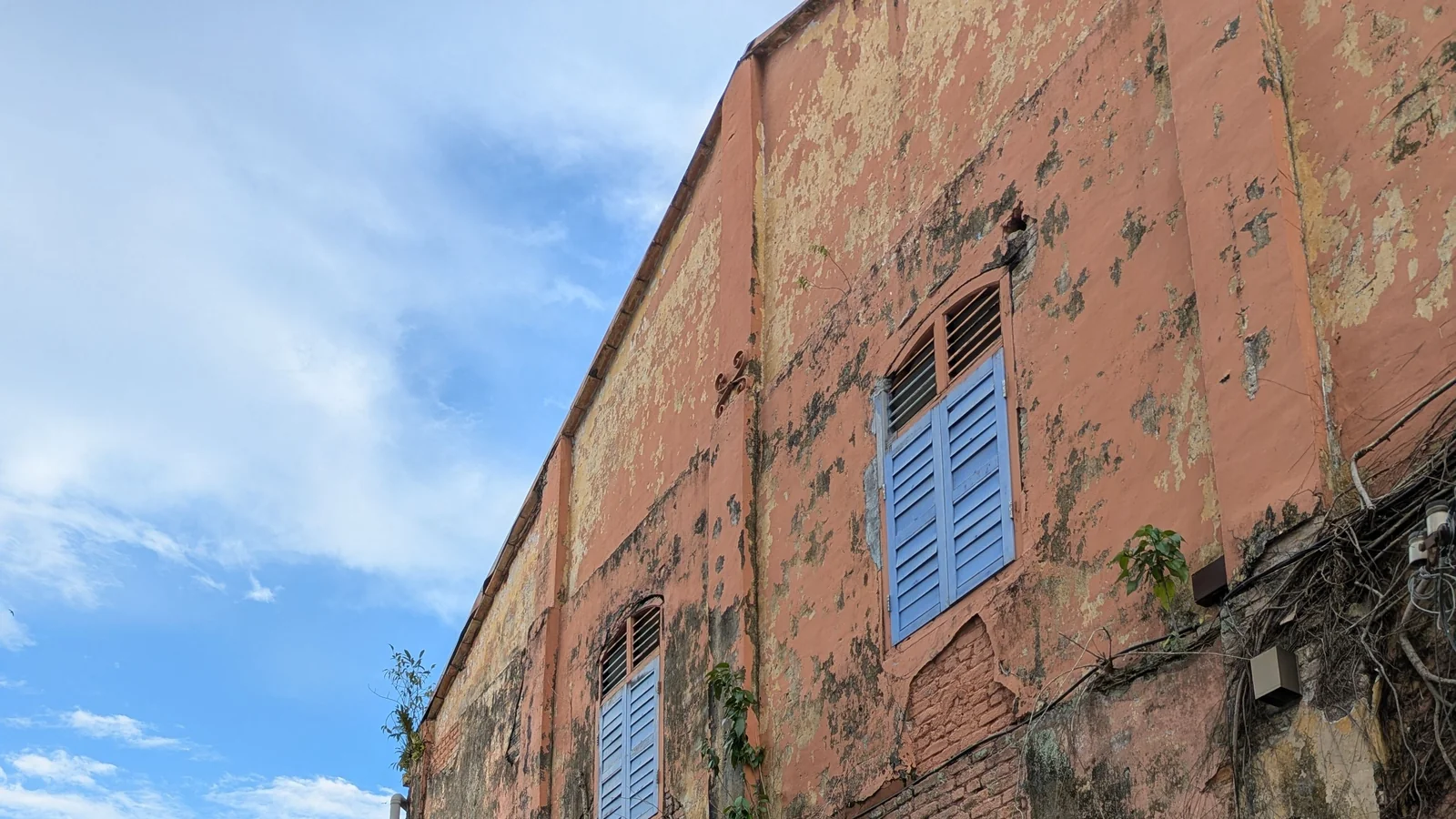 Blue shutters and weathered pink plaster on heritage buildings around Kong Heng in Ipoh.