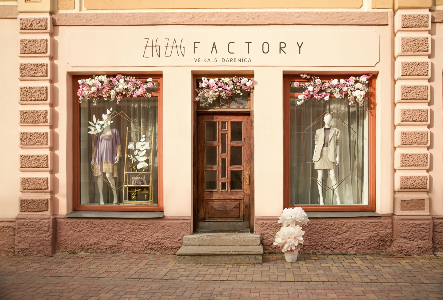 Signed Zig Zag Factory shopfront with decorated windows on Liepājas Street in Kuldīga
