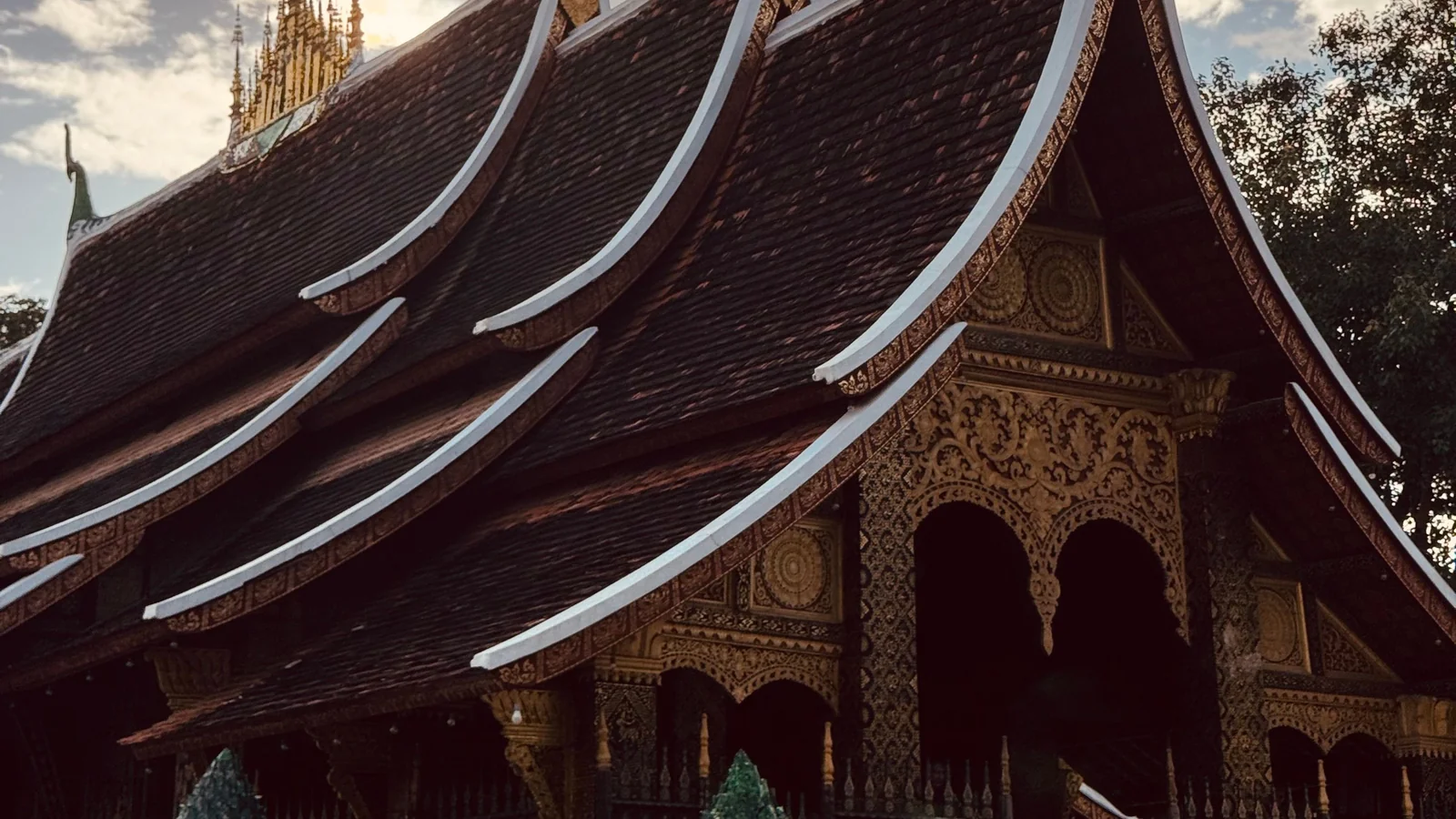 Wat Xieng Thong’s layered roofs and gilded porch in Luang Prabang in evening light.