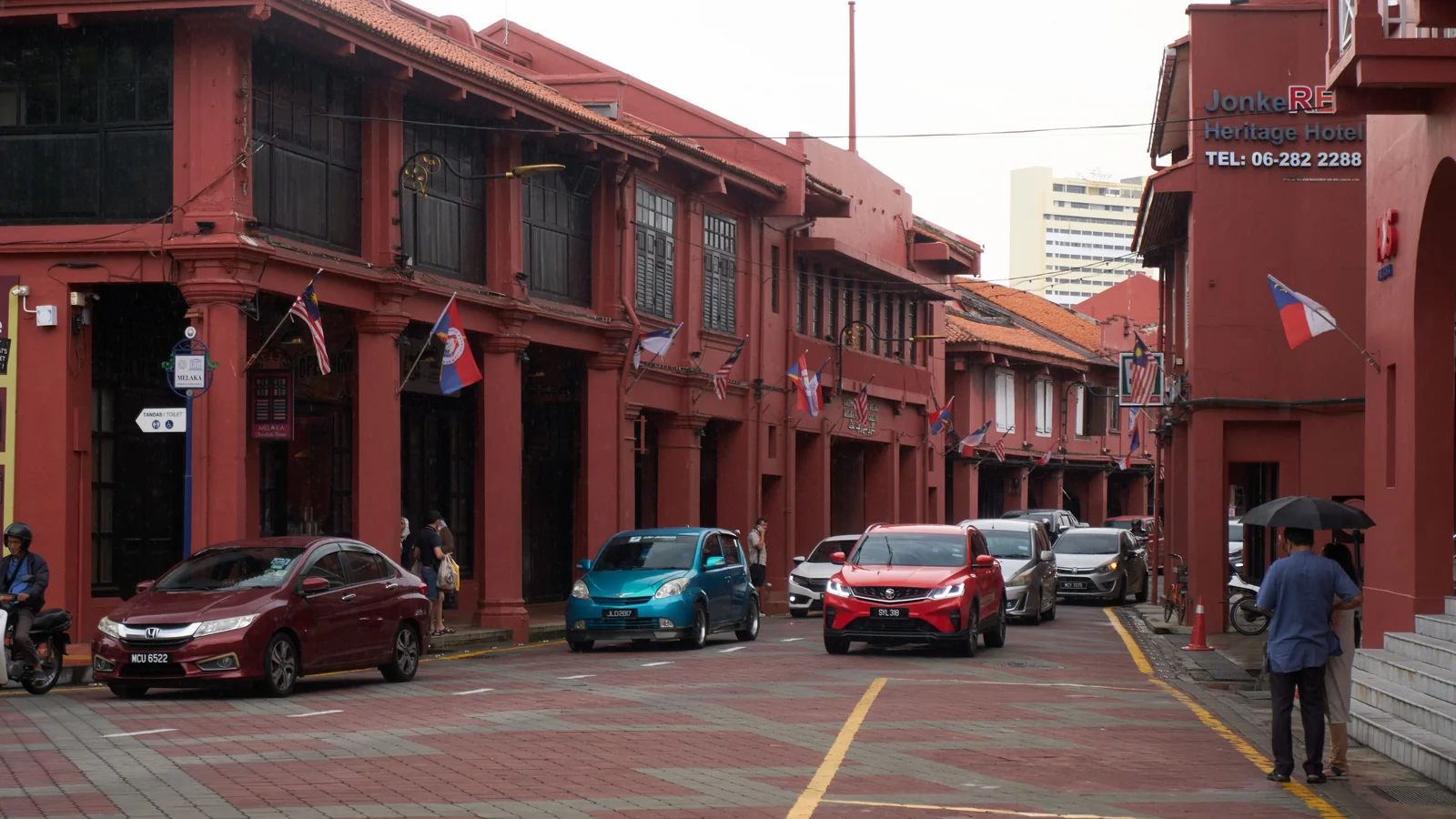 Red heritage shophouses and traffic on Jalan Laksamana near Dutch Square in Malacca.