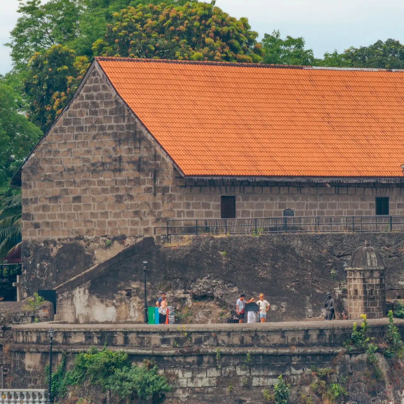 Stone walls and a red-roofed historic building inside Fort Santiago in Manila