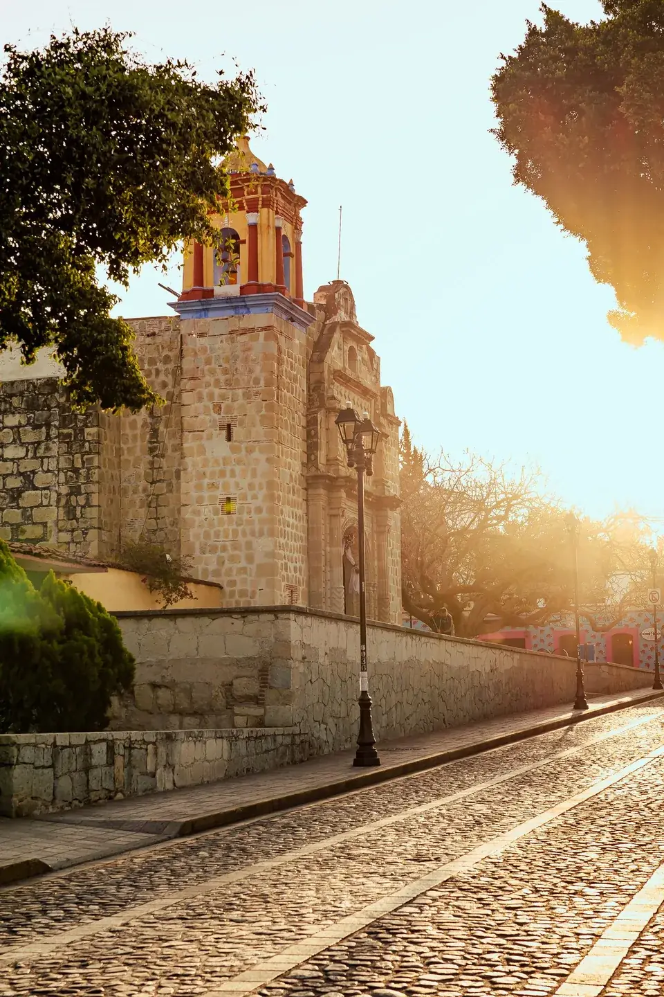 Stone church of San Matías Jalatlaco beside a cobbled street at sunset