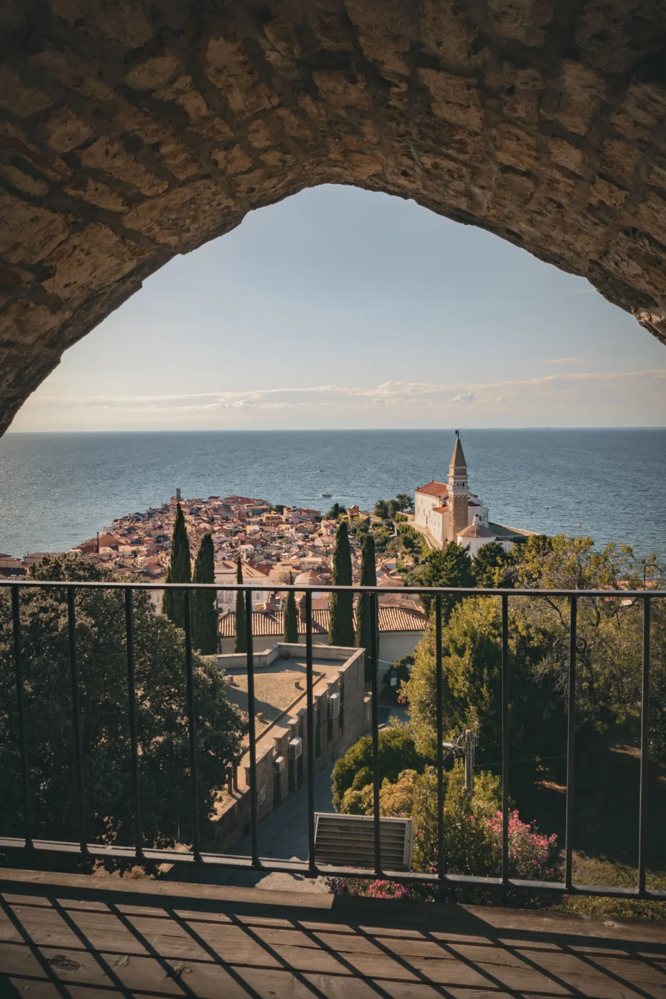 Piran’s rooftops and St George’s church framed by a stone arch in the town walls