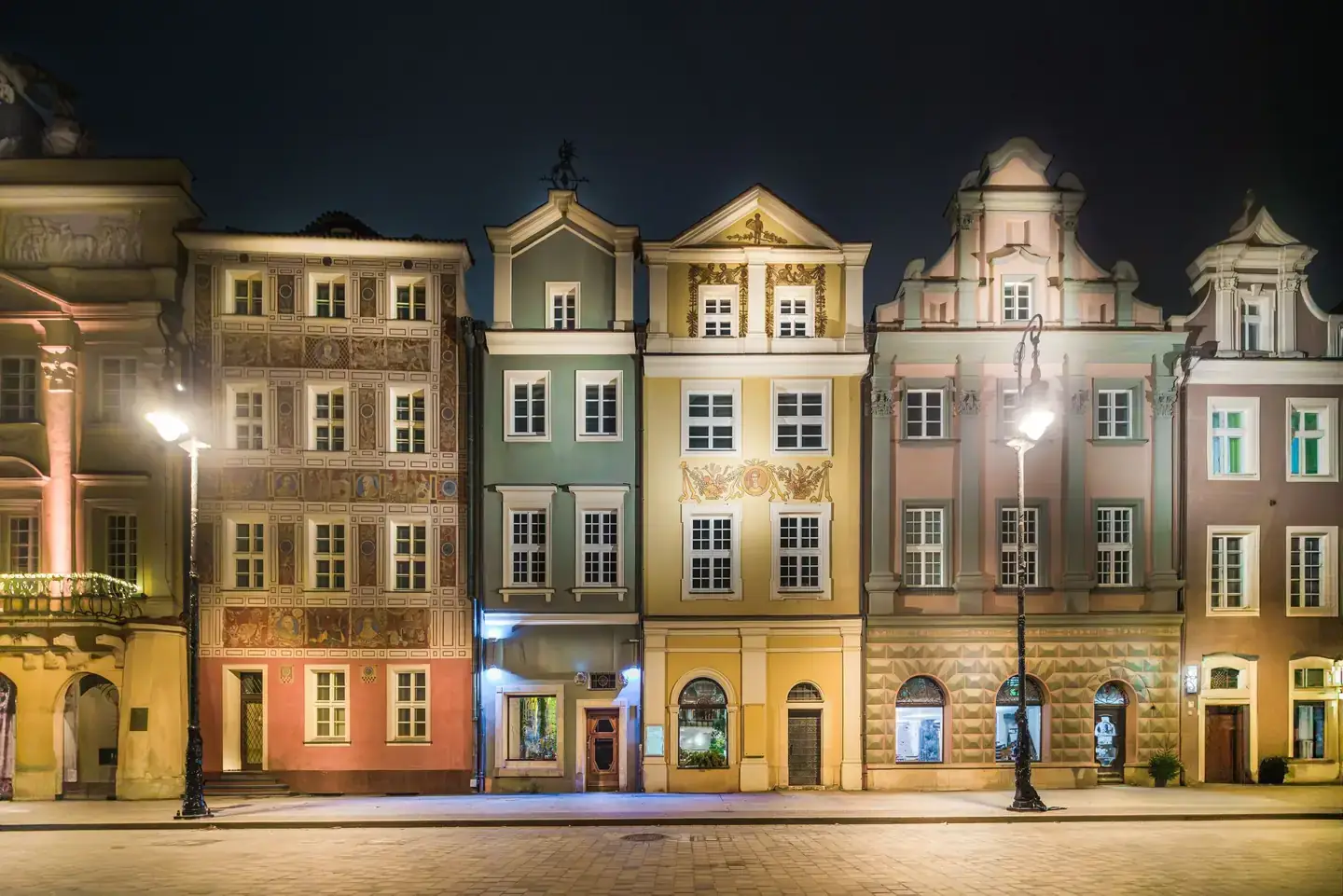 Historic tenement houses illuminated along Poznań’s Old Market Square at night