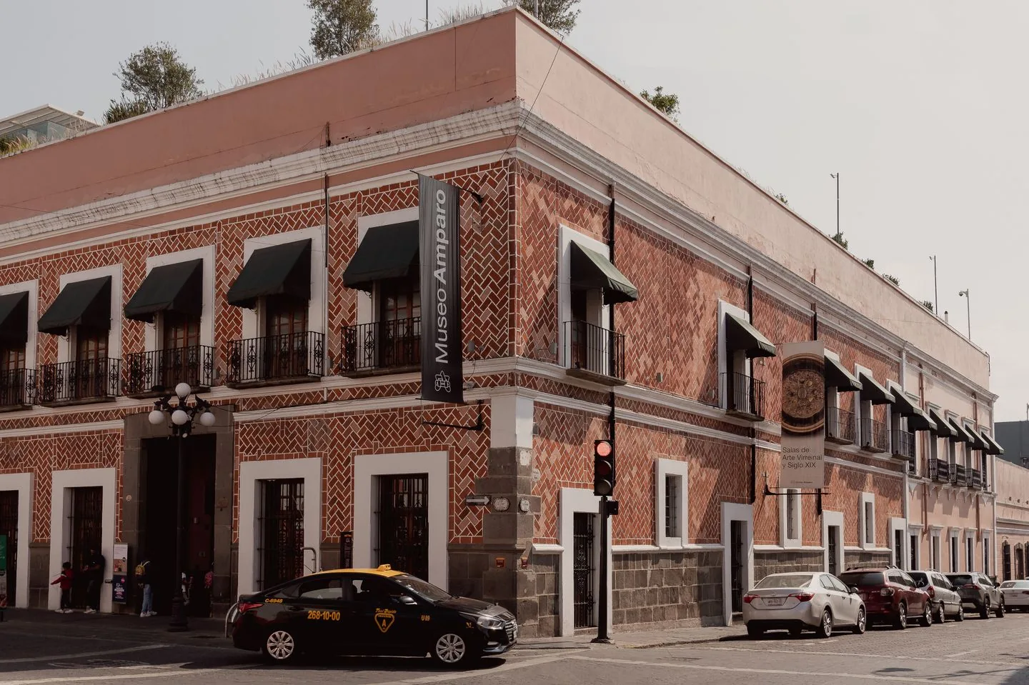 Museo Amparo street corner with red brick, tilework and museum banners in Puebla