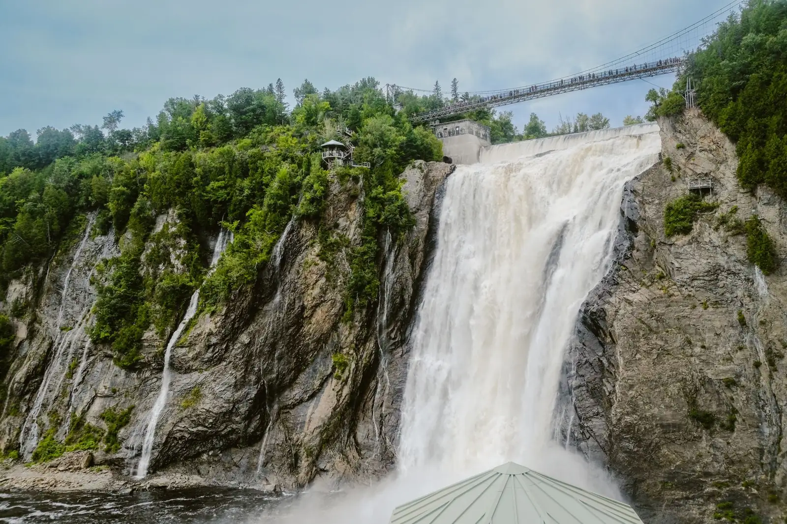 Montmorency Falls cascading below the suspension bridge with green cliffs on both sides