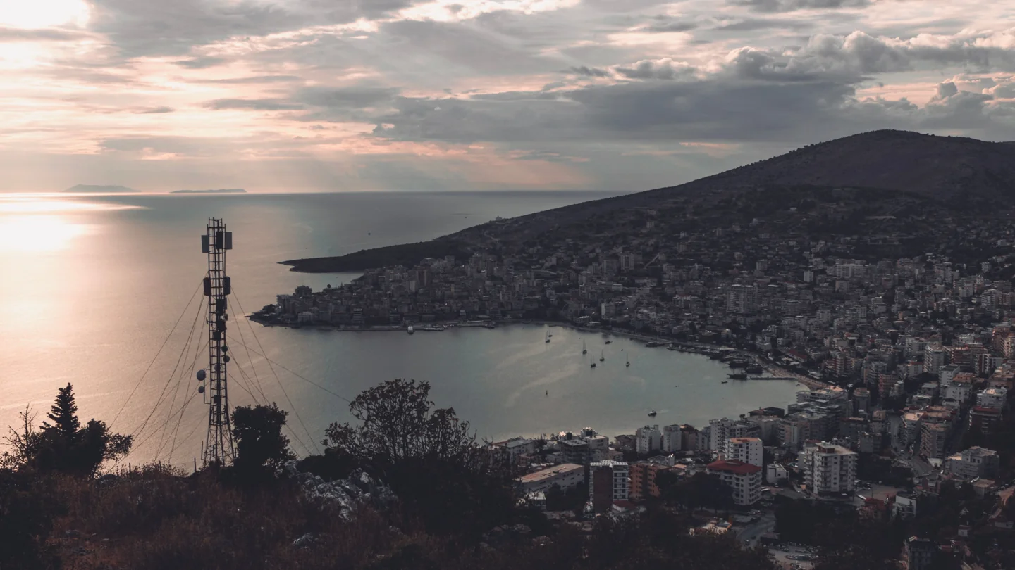 Sarandë’s curved bay and hillside buildings at dusk