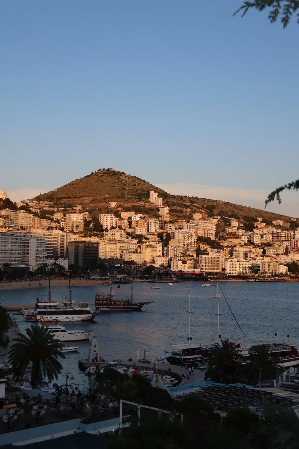 Boats and waterfront buildings along Sarandë’s bay in evening light