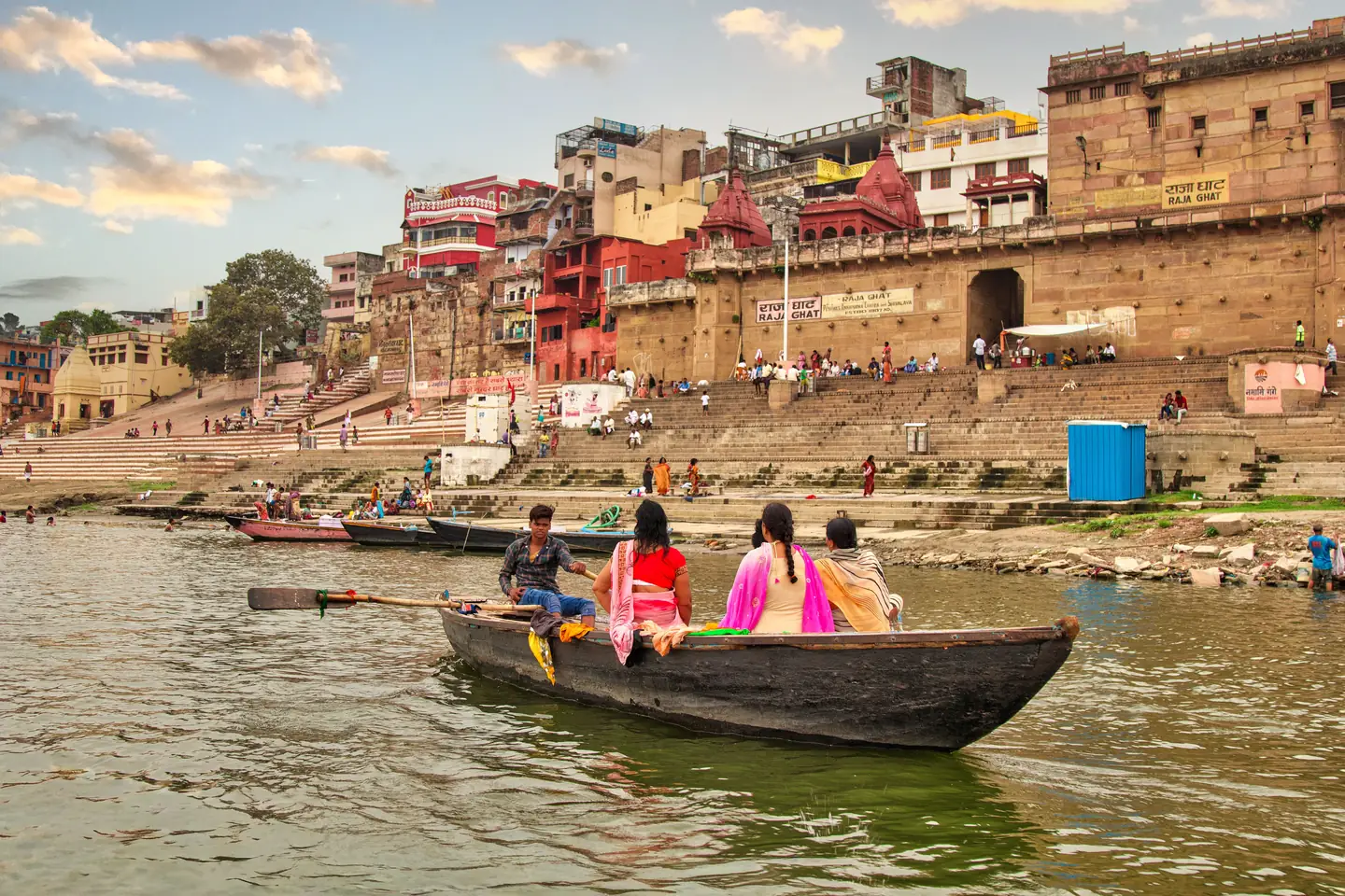 A boat travelling along the Ganges with Varanasi’s ghats behind it