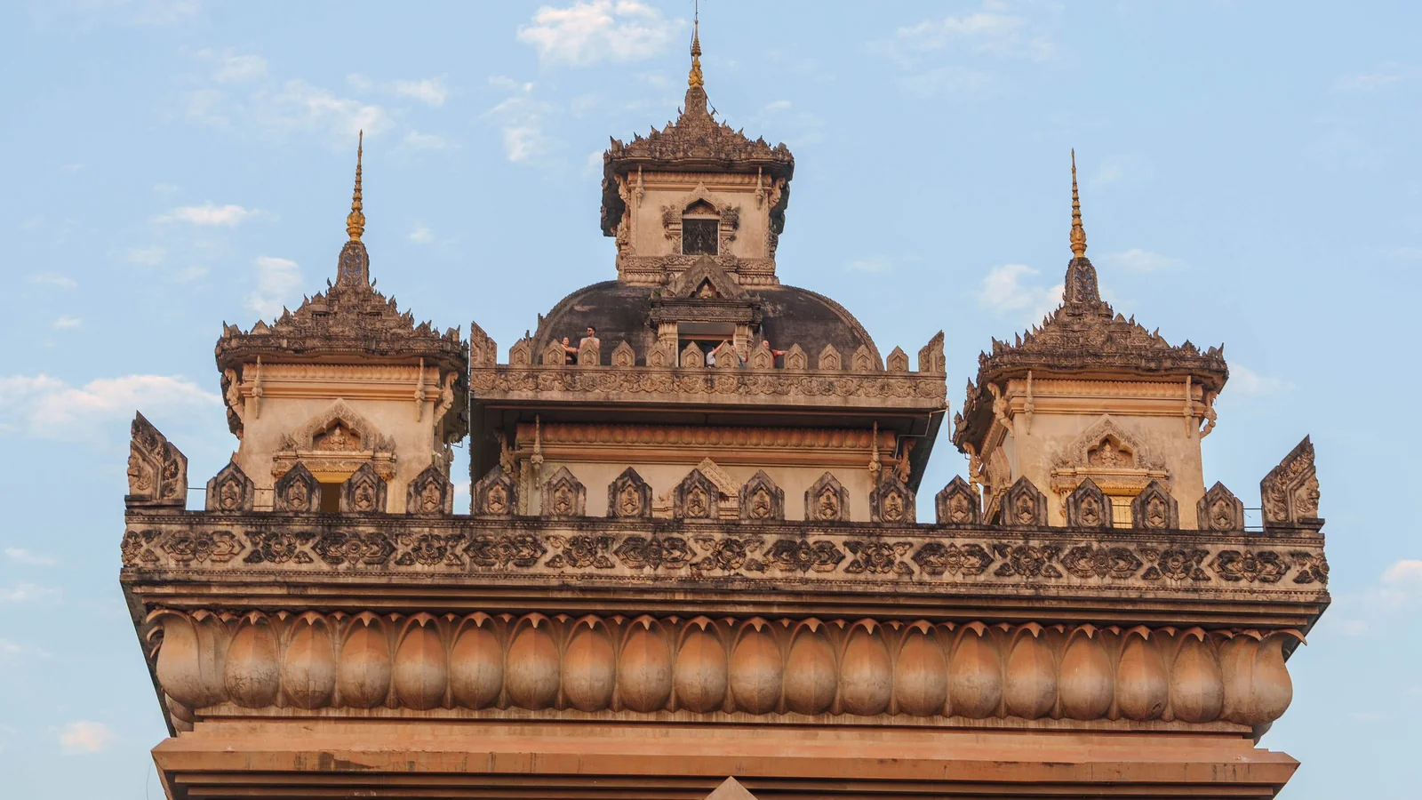 Close view of Patuxai’s carved upper facade and five tiered towers against the sky.