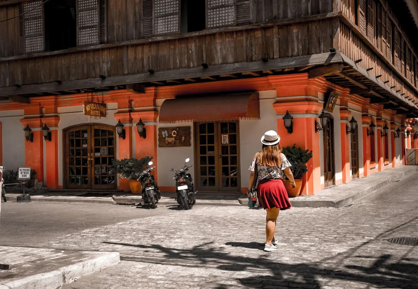 A visitor beside the orange masonry and wooden upper floor of My Vigan Home Hotel in Vigan