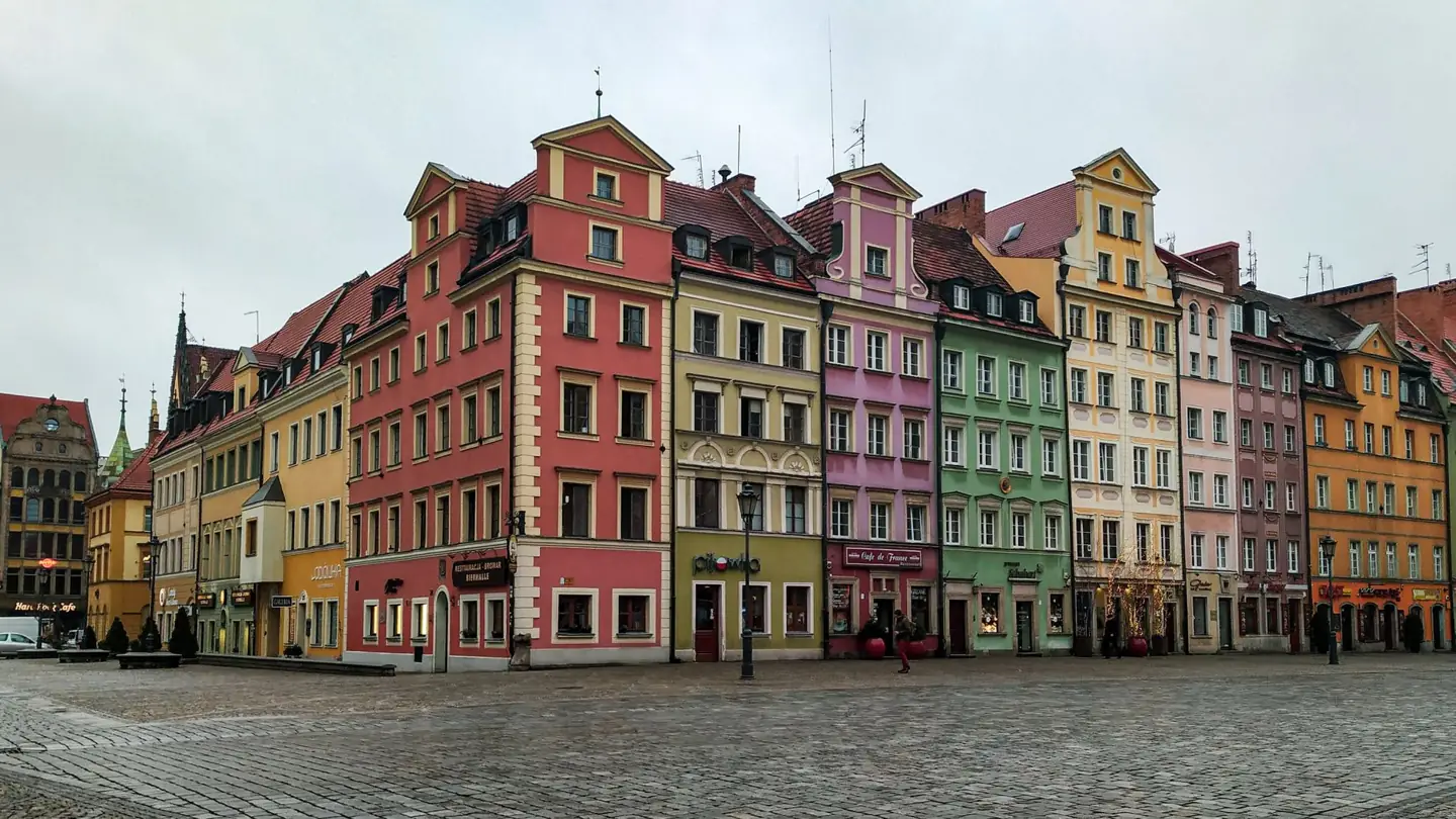 Colourful tenement façades around Wrocław’s Market Square above an open cobbled foreground