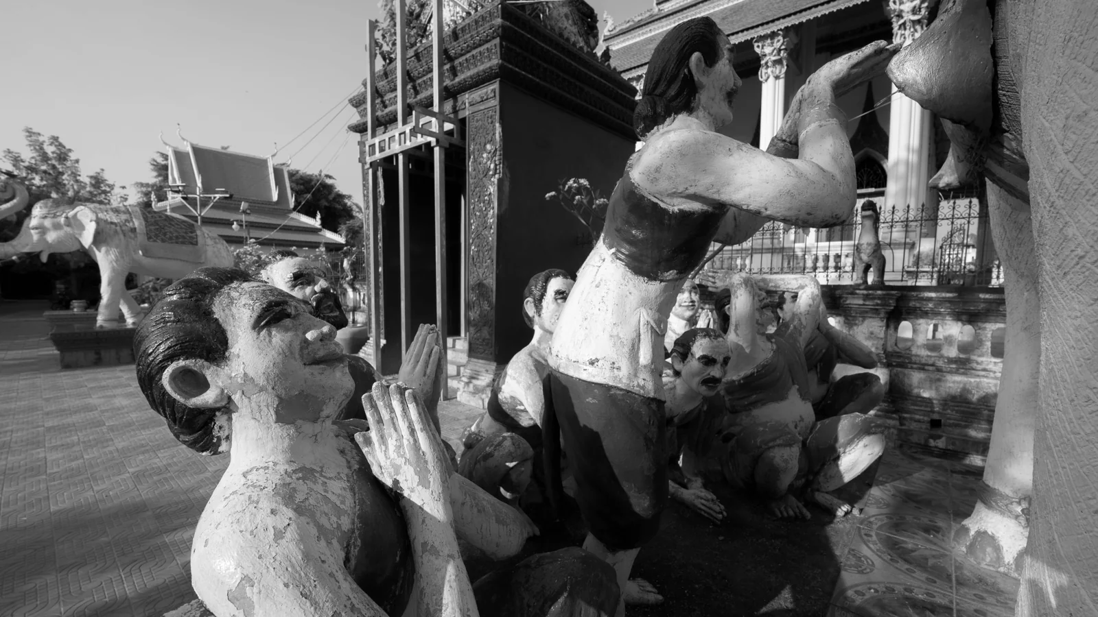 Elephant and kneeling figures beside the temple hall at Battambang’s White Elephant Pagoda, photographed in black and white.