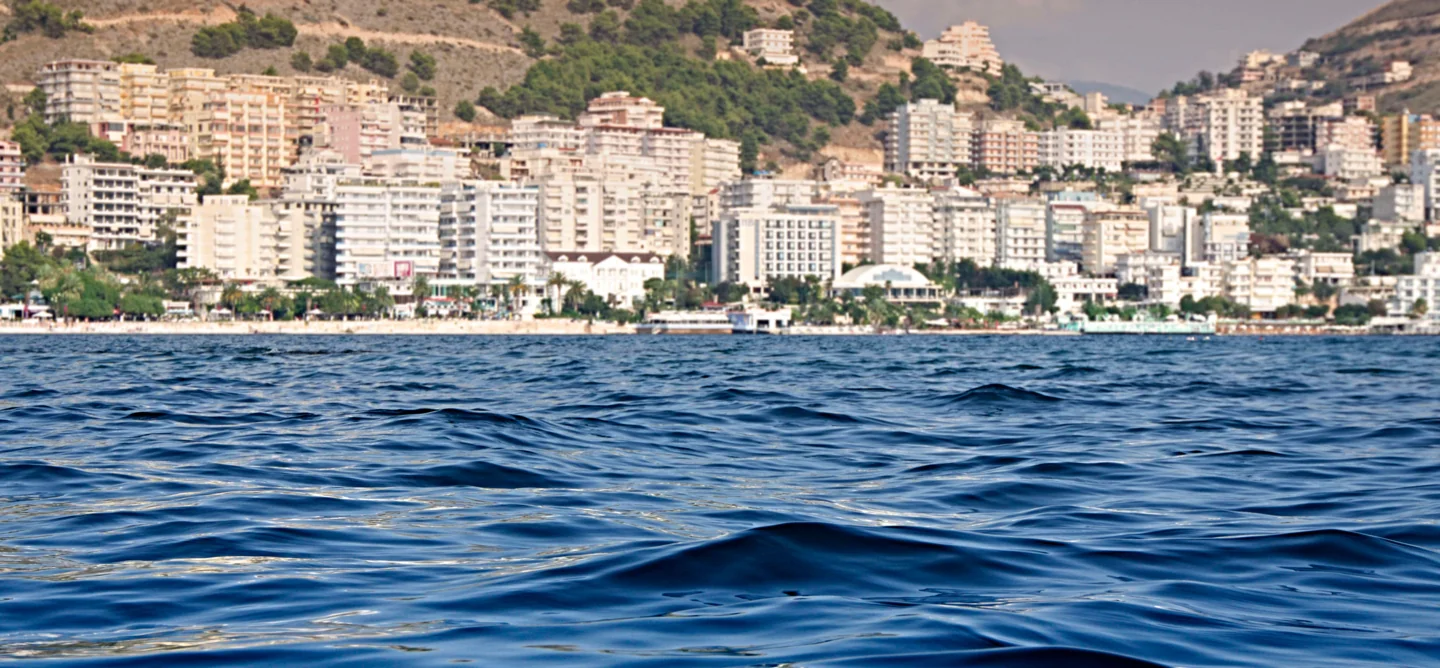 Sarandë waterfront buildings and boats seen across the blue Ionian water